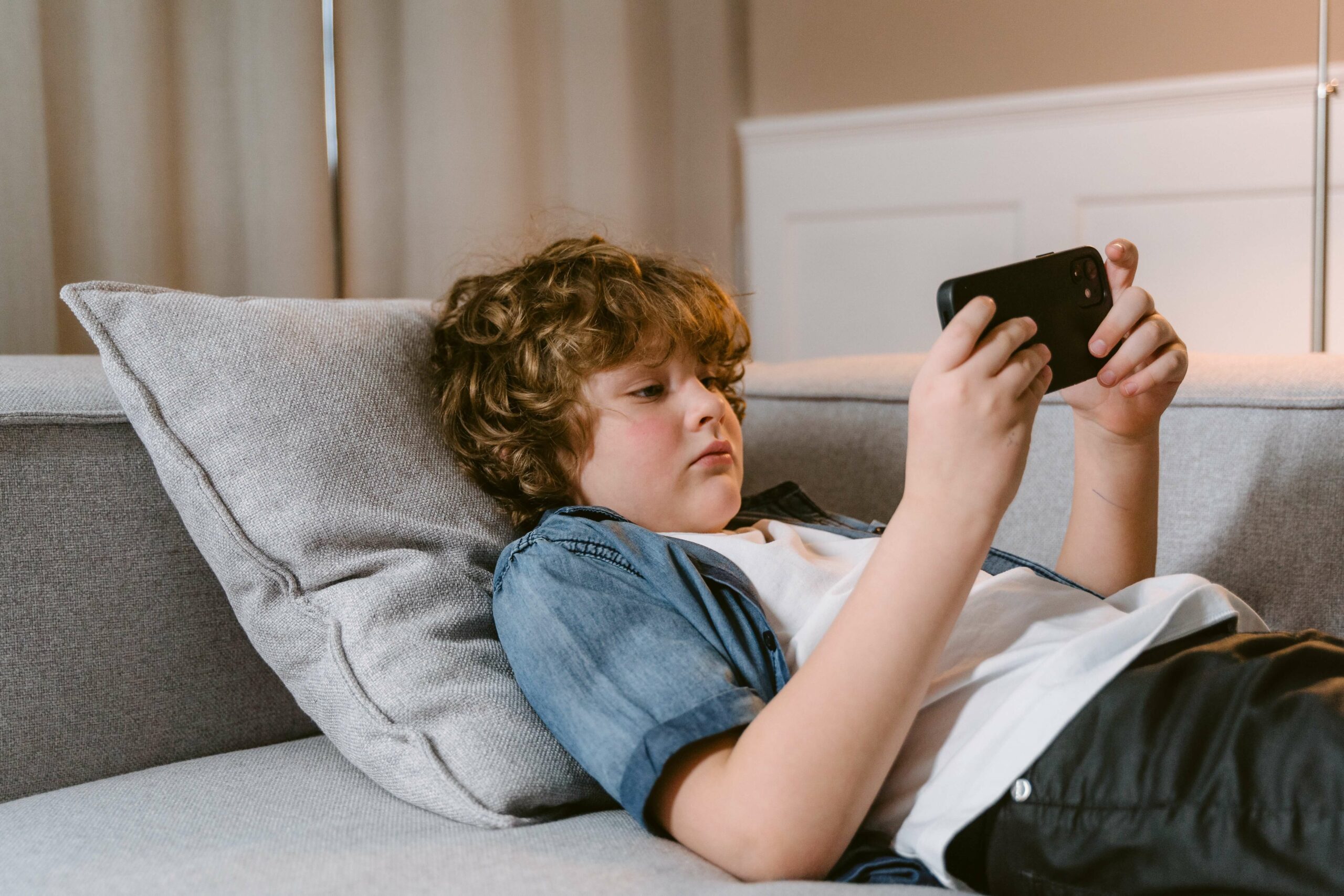 child laying on couch with phone