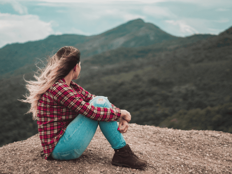 Young woman sitting outside looking at the mountains